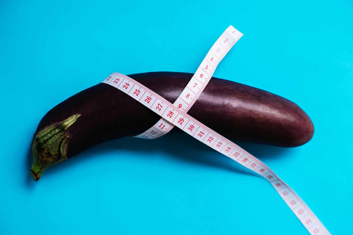 Eggplant with measuring tape wrapped around it, used as a visual metaphor for penile size and augmentation